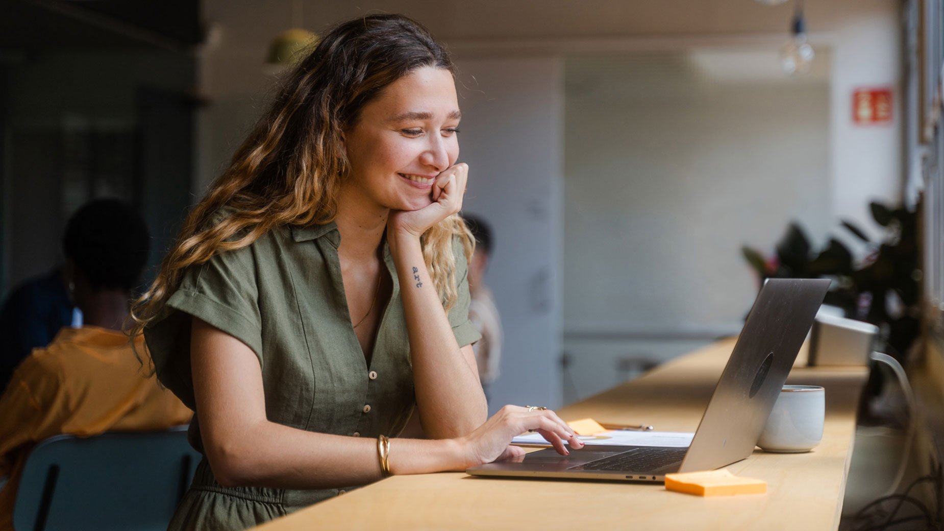 young woman sitting at cafe counter looking at a laptop