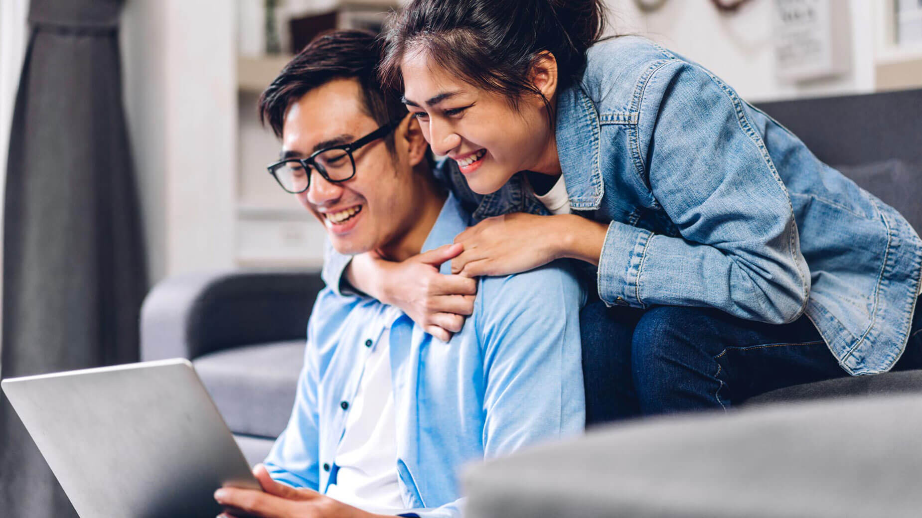 young couple hugging while looking at a laptop